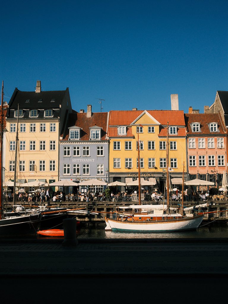Colorful buildings lining Nyhavn harbor in Copenhagen, Denmark on a sunny afternoon. One of the city's most iconic landmarks featured in this detailed 3 day Copenhagen itinerary.